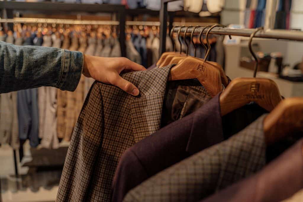 Cropped image of a man's hand searching through coats in a store