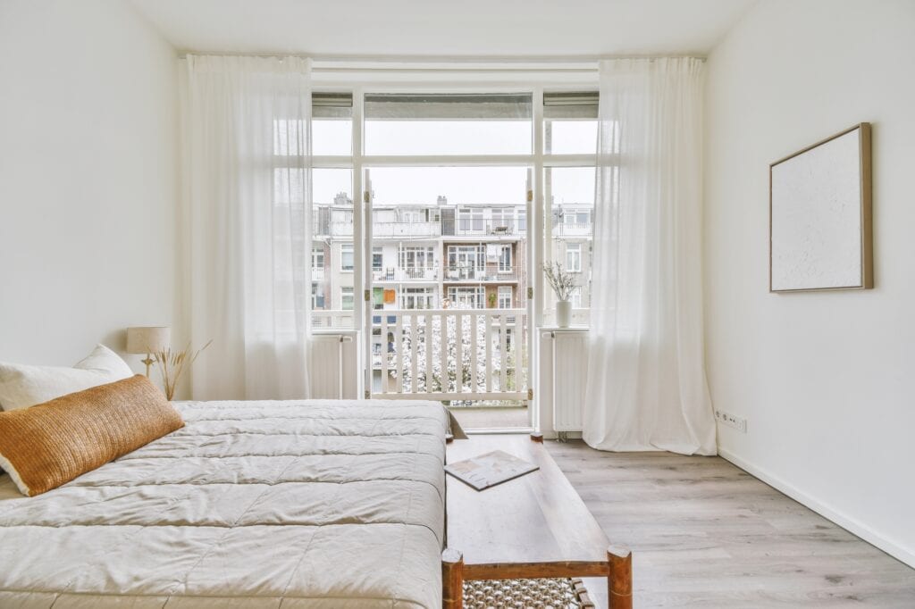 A spacious bedroom in a modern flat with a balcony