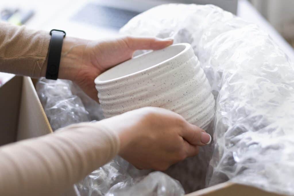 Cropped image of a woman's hands packing a fragile item in a bubble wrap