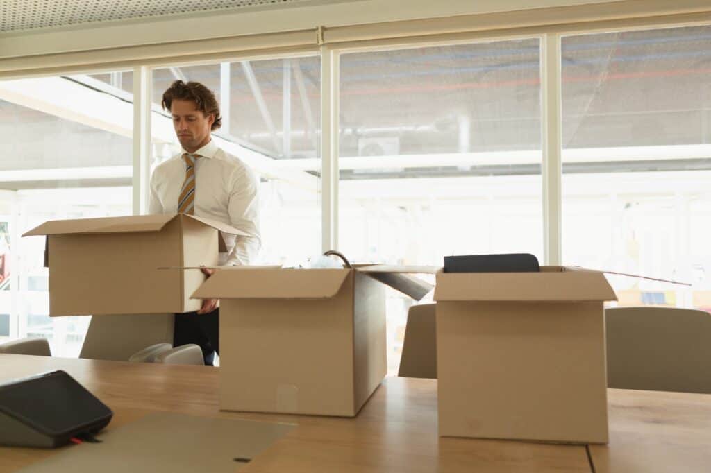 A male employee carrying cardboard into a conference room